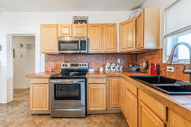 kitchen with backsplash, light brown cabinetry, sink, and stainless steel appliances