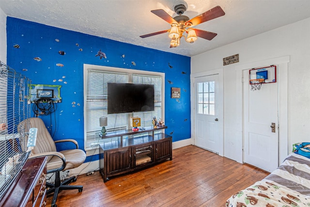 living room with hardwood / wood-style flooring, ceiling fan, and a textured ceiling