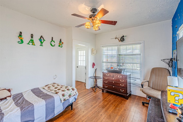 bedroom with hardwood / wood-style flooring, ceiling fan, and a textured ceiling