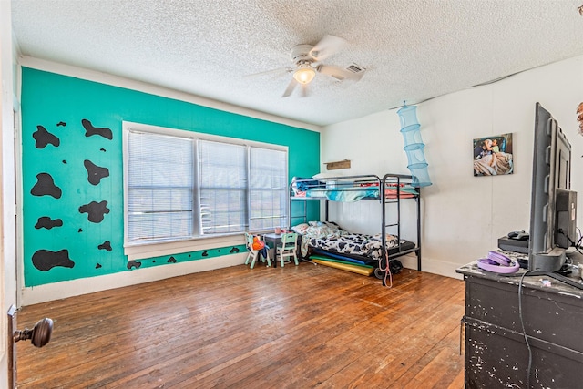 bedroom featuring hardwood / wood-style flooring, ceiling fan, and a textured ceiling