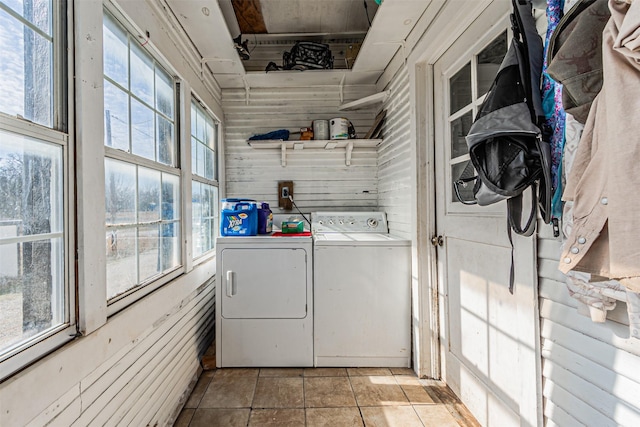 clothes washing area featuring light tile patterned floors, wooden walls, and washing machine and clothes dryer