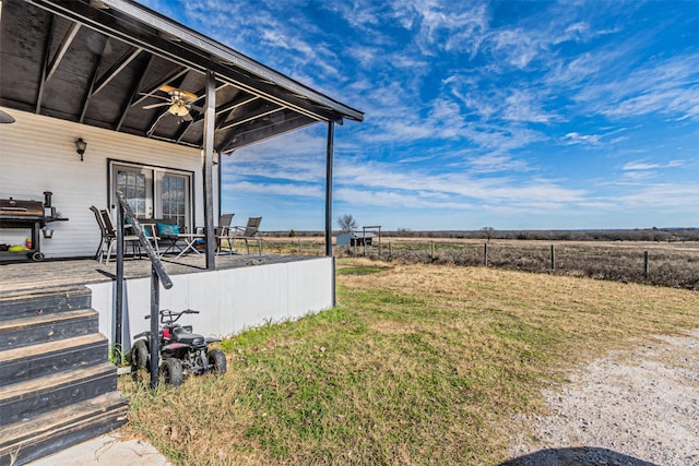 view of yard featuring ceiling fan and a rural view