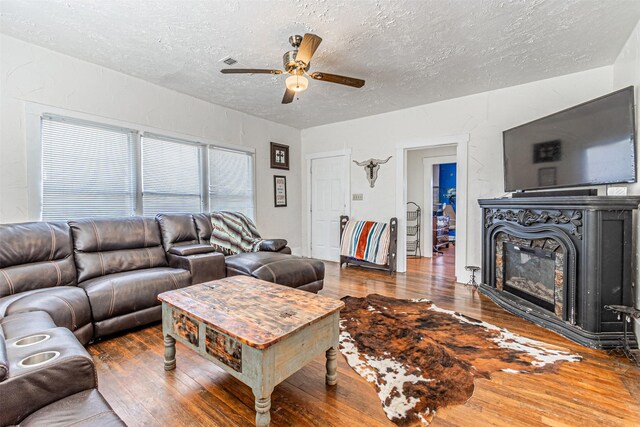 living room featuring a textured ceiling, dark hardwood / wood-style flooring, and ceiling fan