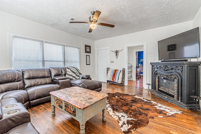 living room featuring wood-type flooring, a textured ceiling, and ceiling fan