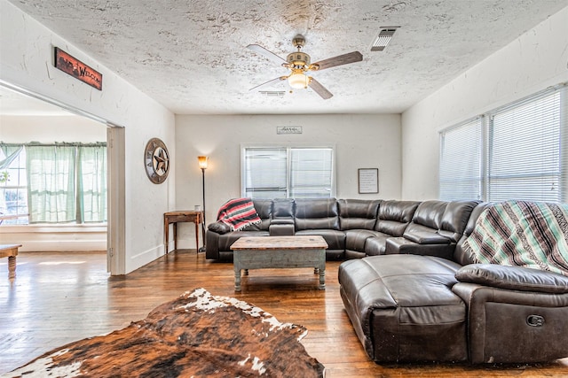 living room featuring ceiling fan, a textured ceiling, and hardwood / wood-style flooring