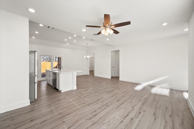 unfurnished living room with ceiling fan with notable chandelier, light wood-type flooring, and sink