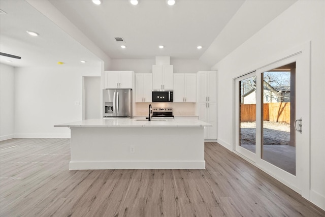 kitchen with a center island with sink, white cabinets, sink, appliances with stainless steel finishes, and light hardwood / wood-style floors