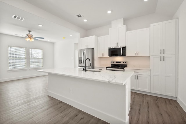 kitchen with a center island with sink, white cabinets, stainless steel appliances, and sink