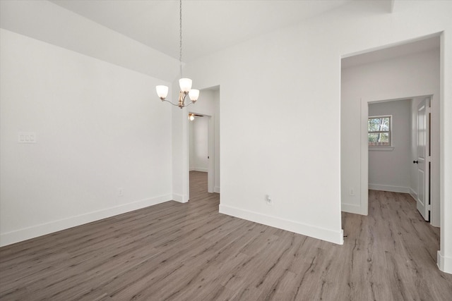 unfurnished room with light wood-type flooring and an inviting chandelier