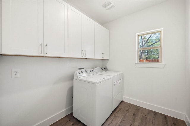 laundry area with cabinets, dark hardwood / wood-style floors, and washing machine and clothes dryer