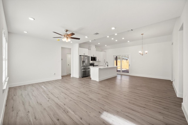 unfurnished living room with ceiling fan with notable chandelier, light wood-type flooring, and sink