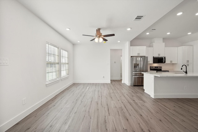 kitchen with light wood-type flooring, stainless steel appliances, ceiling fan, sink, and white cabinets