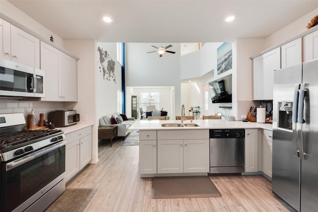 kitchen featuring sink, kitchen peninsula, decorative backsplash, white cabinetry, and stainless steel appliances