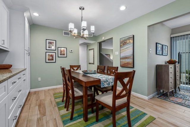 dining area with light hardwood / wood-style floors and a notable chandelier