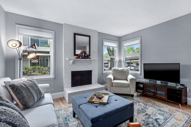 living room with light hardwood / wood-style floors and a brick fireplace