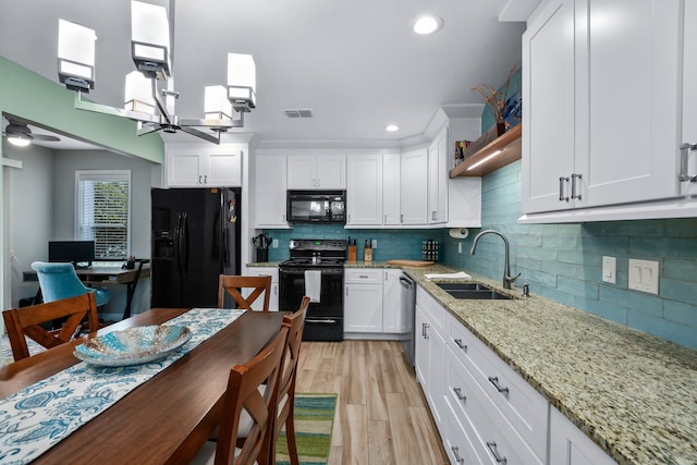 kitchen with light wood-type flooring, ceiling fan, sink, black appliances, and white cabinetry