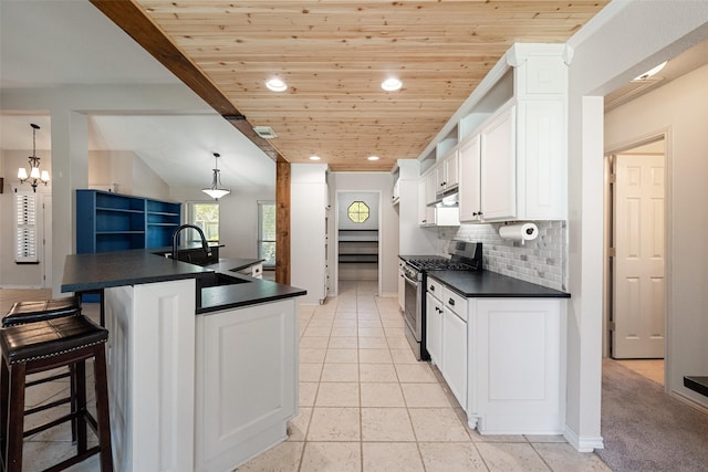 kitchen featuring white cabinets, gas stove, hanging light fixtures, and wood ceiling