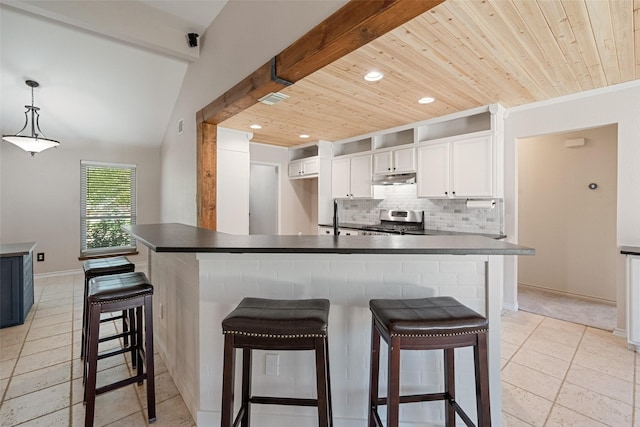 kitchen with white cabinets, a kitchen bar, backsplash, and stainless steel stove