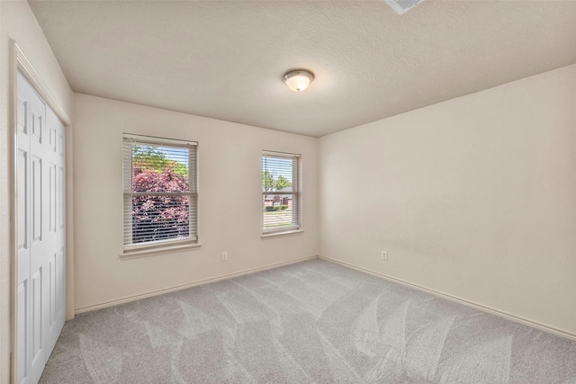 carpeted empty room with a textured ceiling