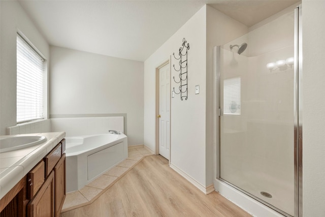 bathroom with plus walk in shower, wood-type flooring, vanity, and a healthy amount of sunlight