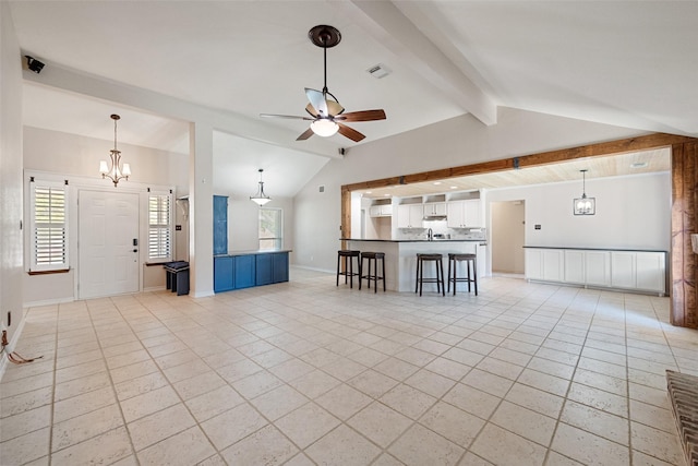 unfurnished living room featuring vaulted ceiling with beams, light tile patterned floors, ceiling fan with notable chandelier, and a wealth of natural light