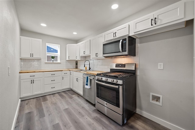 kitchen featuring white cabinets, sink, appliances with stainless steel finishes, butcher block countertops, and light hardwood / wood-style floors