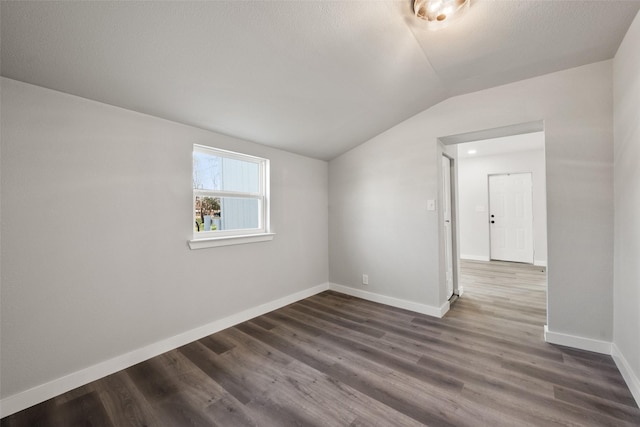 empty room featuring dark wood-type flooring and vaulted ceiling