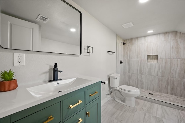 bathroom featuring tiled shower, vanity, and toilet