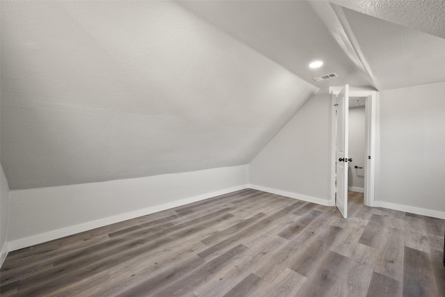 bonus room with hardwood / wood-style floors, a textured ceiling, and lofted ceiling