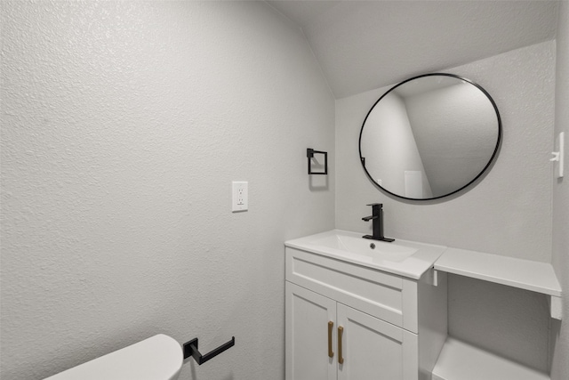 bathroom with vanity, toilet, and vaulted ceiling