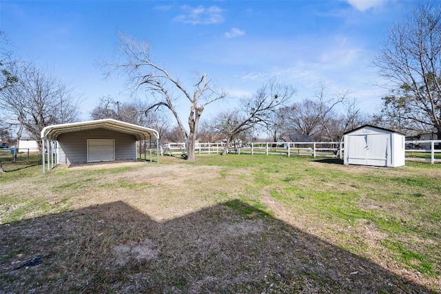 view of yard featuring a carport, a storage unit, and a rural view