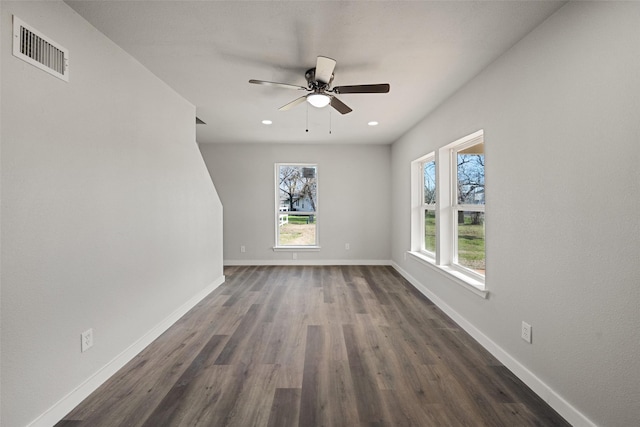 spare room with ceiling fan, dark wood-type flooring, and a wealth of natural light