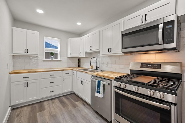 kitchen with wood counters, appliances with stainless steel finishes, and white cabinetry