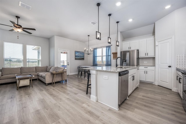 kitchen featuring decorative backsplash, a kitchen island with sink, white cabinets, and appliances with stainless steel finishes