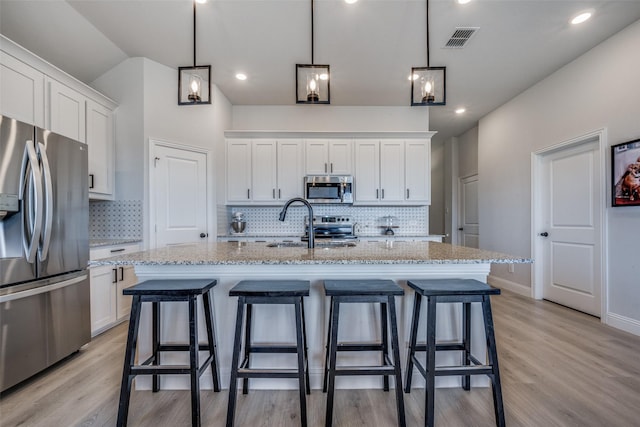 kitchen with pendant lighting, white cabinetry, an island with sink, and appliances with stainless steel finishes