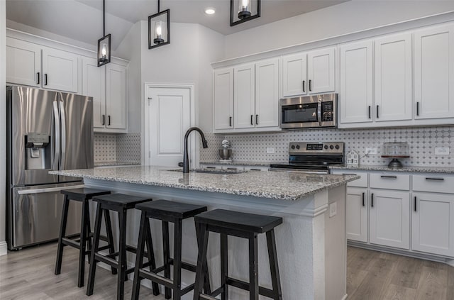 kitchen featuring white cabinets, stainless steel appliances, a center island with sink, and sink