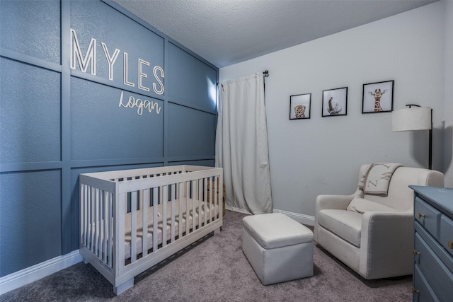 carpeted bedroom featuring a textured ceiling and a nursery area