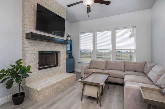 living room featuring ceiling fan, light hardwood / wood-style floors, and a fireplace