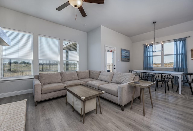 living room featuring ceiling fan with notable chandelier and light hardwood / wood-style flooring