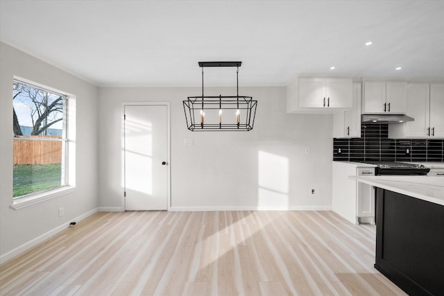 kitchen with white cabinetry, decorative light fixtures, tasteful backsplash, and light wood-type flooring