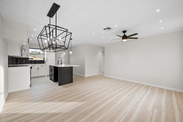 kitchen with white cabinetry, tasteful backsplash, decorative light fixtures, light hardwood / wood-style flooring, and a kitchen island