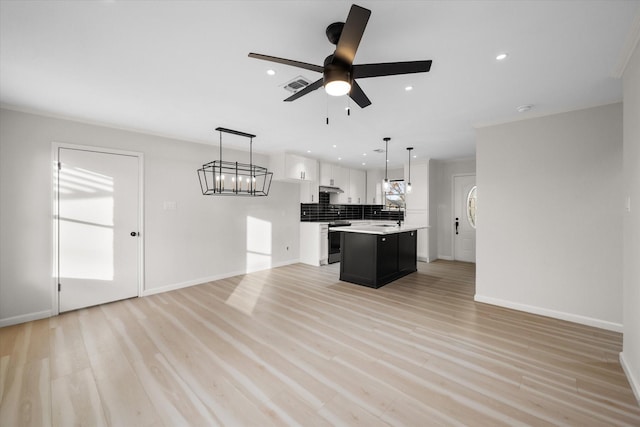 kitchen featuring stainless steel electric stove, decorative light fixtures, tasteful backsplash, white cabinets, and a center island