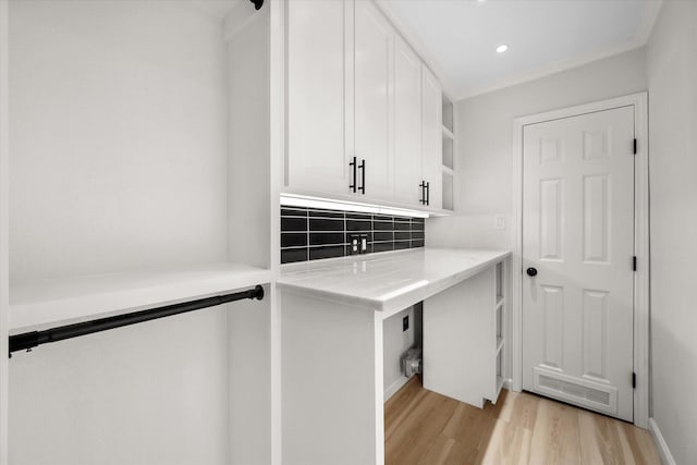 laundry room with crown molding and light hardwood / wood-style floors