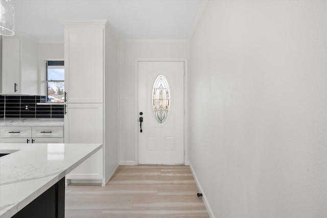 doorway with crown molding and light hardwood / wood-style floors