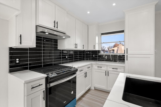 kitchen with sink, gas stove, white cabinetry, light wood-type flooring, and backsplash