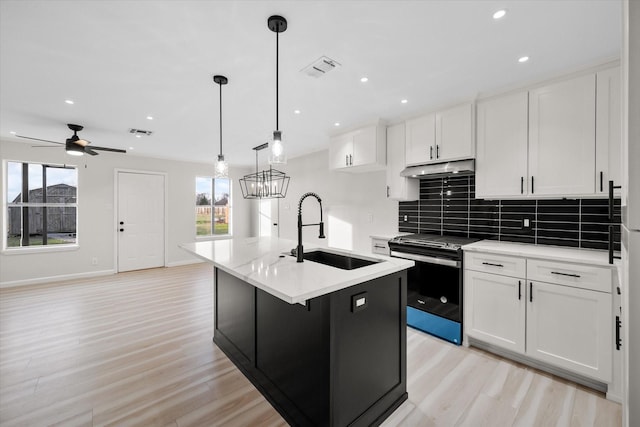 kitchen featuring a kitchen island with sink, sink, white cabinetry, and stainless steel range with electric cooktop