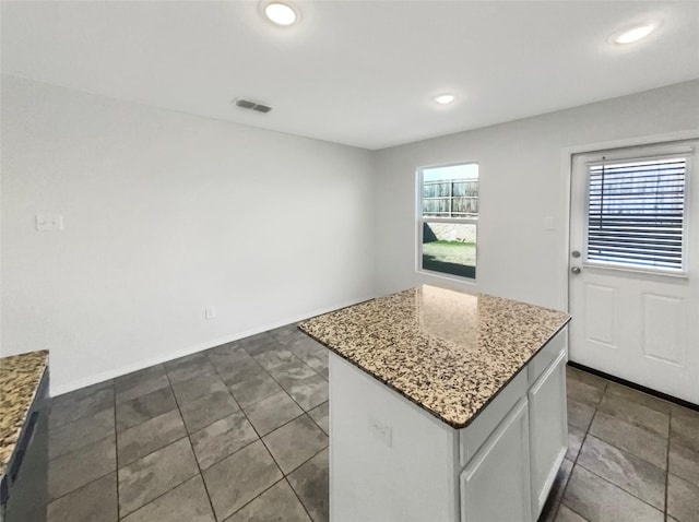 kitchen with white cabinets, a center island, and light stone counters