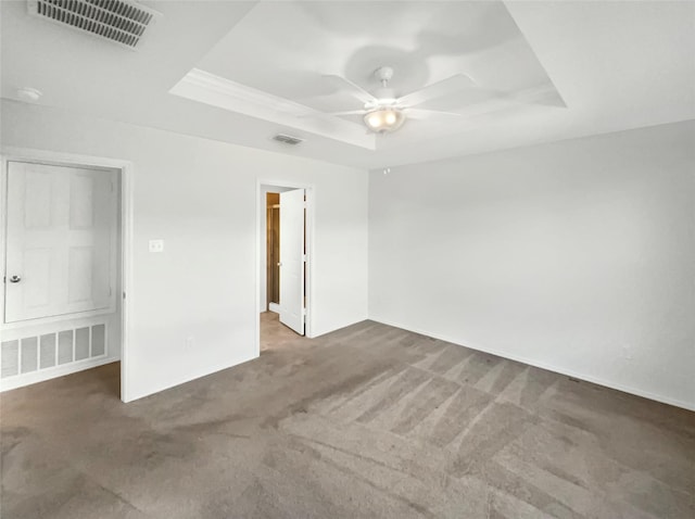 carpeted spare room featuring a raised ceiling and ceiling fan