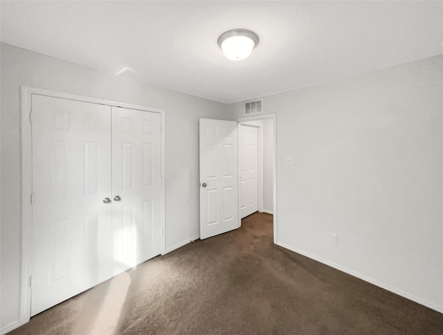 unfurnished bedroom with dark carpet and a closet