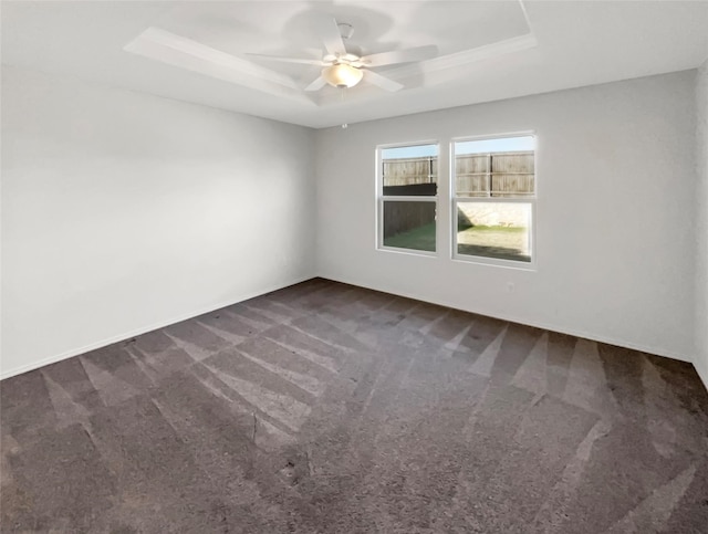 unfurnished room featuring dark carpet, a raised ceiling, and ceiling fan